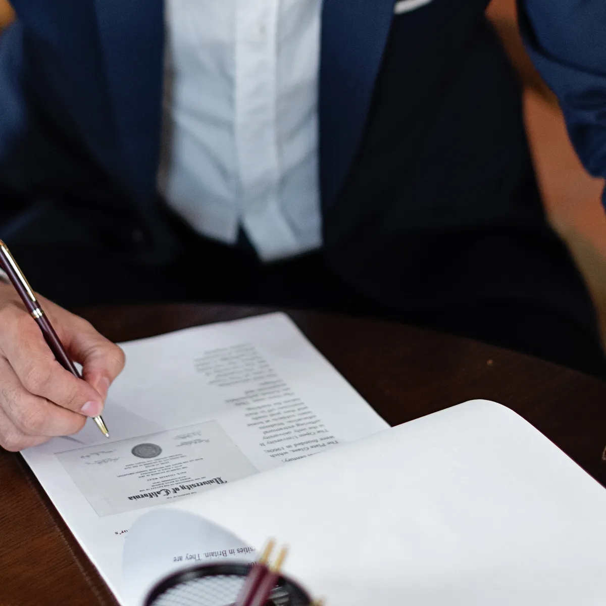 Firma de un documento sobre un escritorio de madera oscura